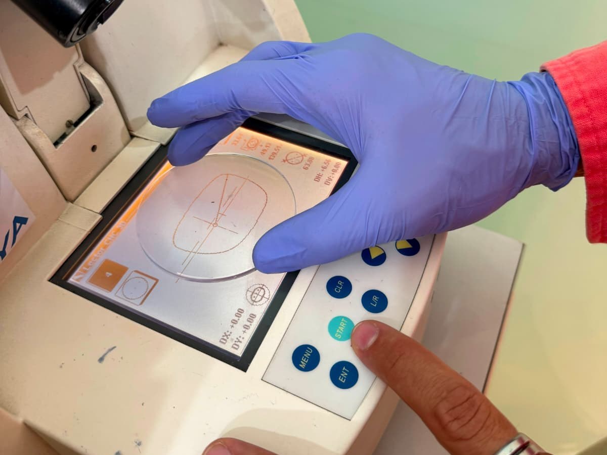 Óptico-optometrista tallando una lente graduada en el taller de Óptica Palmanova, en Calvià